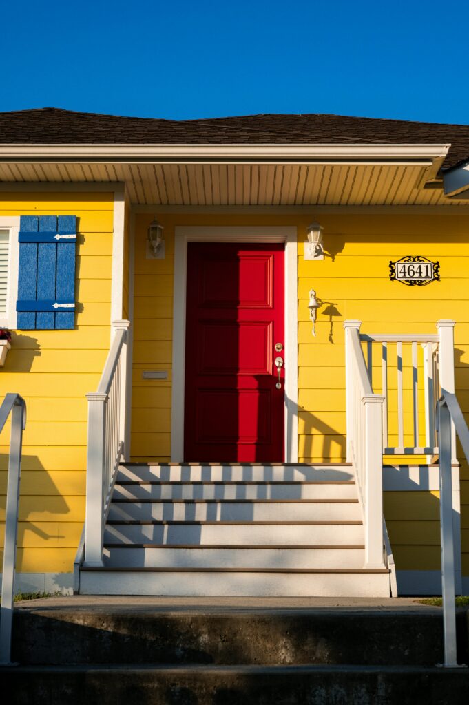 Colorful house exterior featuring yellow walls and a striking red door.